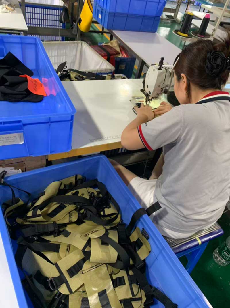 Sewing bench bar-tacking webbing strap assemblies beside colour-separated bins